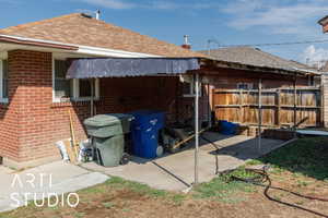 Rear view of property featuring brick siding and roof with shingles