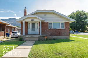 Bungalow-style home featuring brick siding, a chimney, a front lawn, and a mountain view
