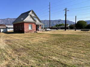 View of side of home with a mountain view, a lawn, covered porch, and brick siding