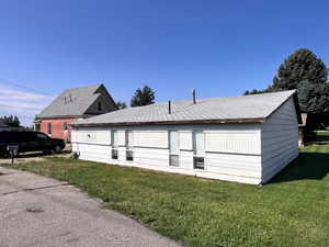 Back of property featuring a lawn and roof with shingles