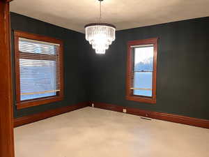 Empty room featuring baseboards and a chandelier