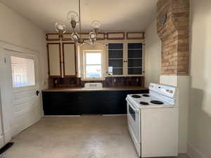 Kitchen featuring white range with electric cooktop, backsplash, hanging light fixtures, and a chandelier