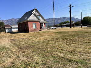 View of front facade with a mountain view, a front lawn, a porch, and brick siding