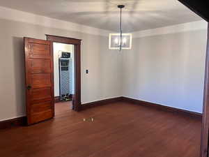 Spare room with dark wood-style floors, a chandelier, and a heating unit