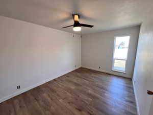 Unfurnished room featuring dark wood finished floors and ceiling fan