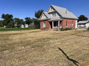 View of front of house featuring a front lawn, a porch, brick siding, and a shingled roof