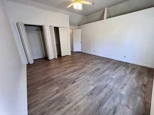 Unfurnished bedroom with two closets, light wood-style flooring, a ceiling fan, and vaulted ceiling