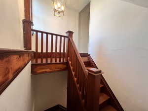 Staircase featuring a textured ceiling and a chandelier
