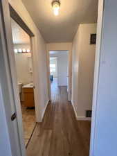 Hallway with dark wood-type flooring and a textured ceiling