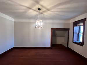 Unfurnished dining area featuring dark wood-style floors, a chandelier, and a textured ceiling