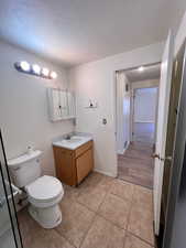 Half bathroom featuring vanity, light tile patterned floors, and a textured ceiling
