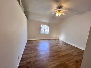 Unfurnished room with dark wood finished floors, a textured ceiling, lofted ceiling, and ceiling fan
