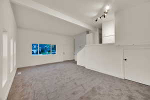 Unfurnished living room featuring beam ceiling and carpet flooring