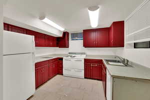 Kitchen featuring white appliances, light countertops, open shelves, and red cabinetry