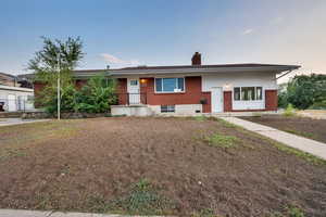 View of front of house featuring brick siding and a chimney