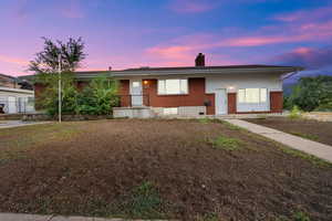 View of front of house featuring a chimney and brick siding