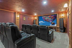 Home theater room featuring a textured ceiling, crown molding, light colored carpet, and recessed lighting