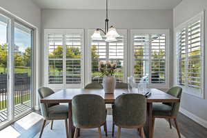 Dining area with plenty of natural light, wood finished floors, and a chandelier