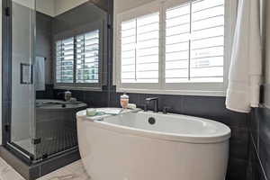 Bathroom featuring tile walls, a freestanding tub, a shower stall, and marble finish floors