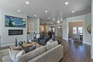 Living area featuring recessed lighting, dark wood-style flooring, a textured ceiling, and a glass covered fireplace
