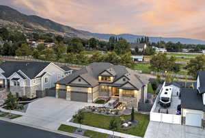 View of front facade featuring a gate, concrete driveway, stone siding, and an attached garage