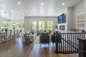 Living room with a textured ceiling, recessed lighting, dark wood finished floors, and a glass covered fireplace