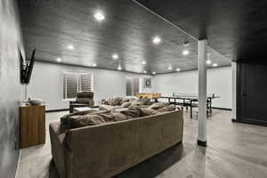 Living room with a textured ceiling, recessed lighting, and finished concrete flooring