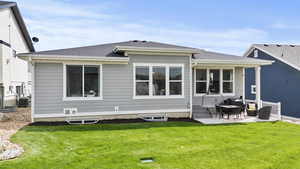 Rear view of property featuring a patio, roof with shingles, and a lawn