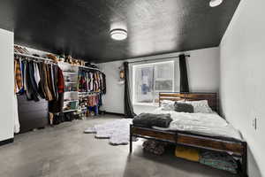 Bedroom with a textured ceiling, finished concrete floors, and a closet