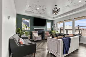 Living room featuring a tray ceiling and a glass covered fireplace