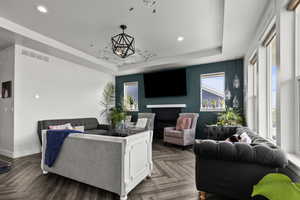 Living room featuring a tray ceiling, recessed lighting, and a fireplace