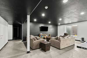 Living area with a textured ceiling, recessed lighting, and finished concrete flooring