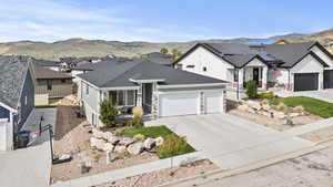 View of front of property with a mountain view, an attached garage, driveway, a residential view, and roof with shingles