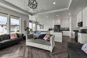 Living area featuring recessed lighting, a tray ceiling, and a chandelier