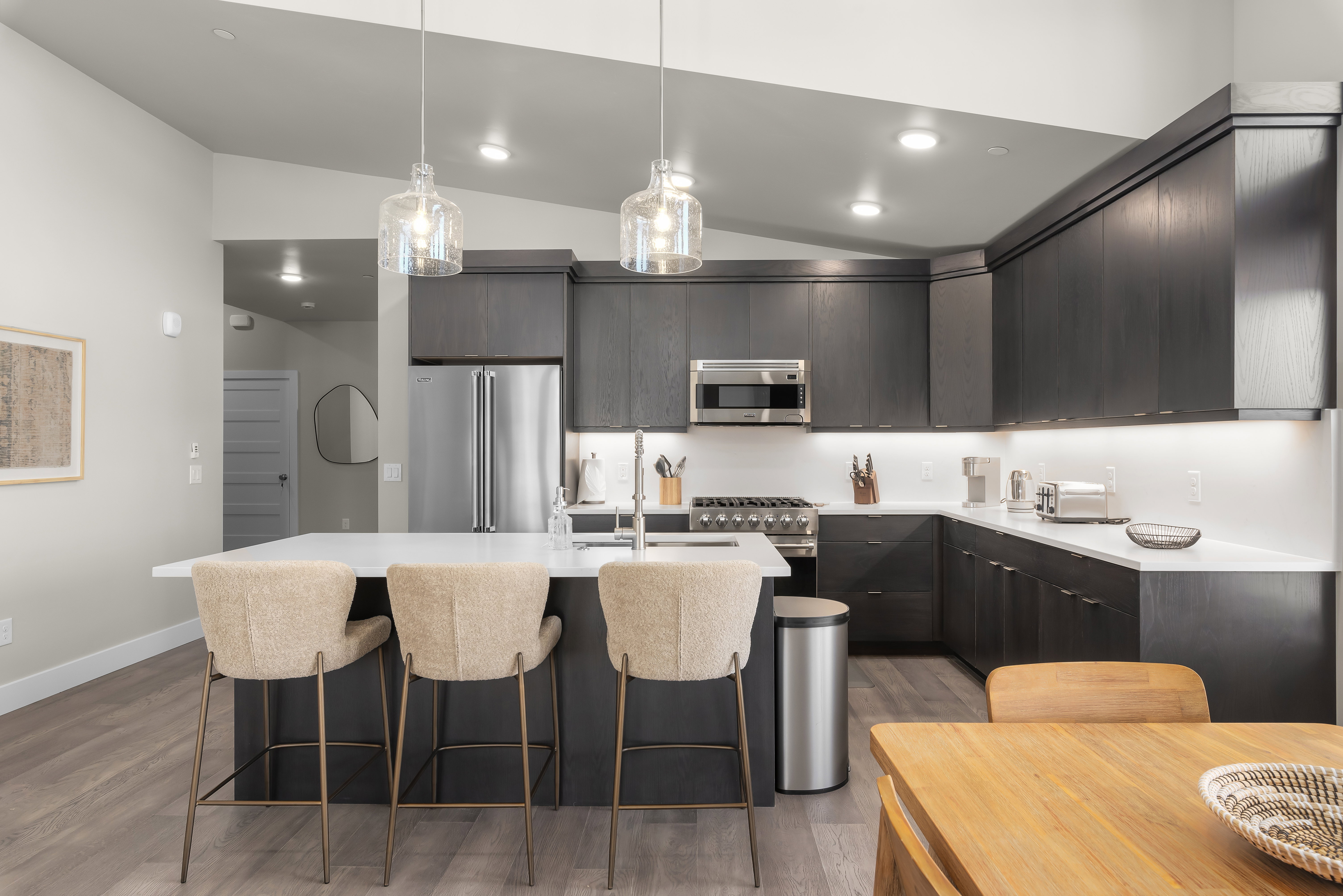 Kitchen featuring modern cabinets, vaulted ceiling, decorative light fixtures, premium appliances, and a breakfast bar
