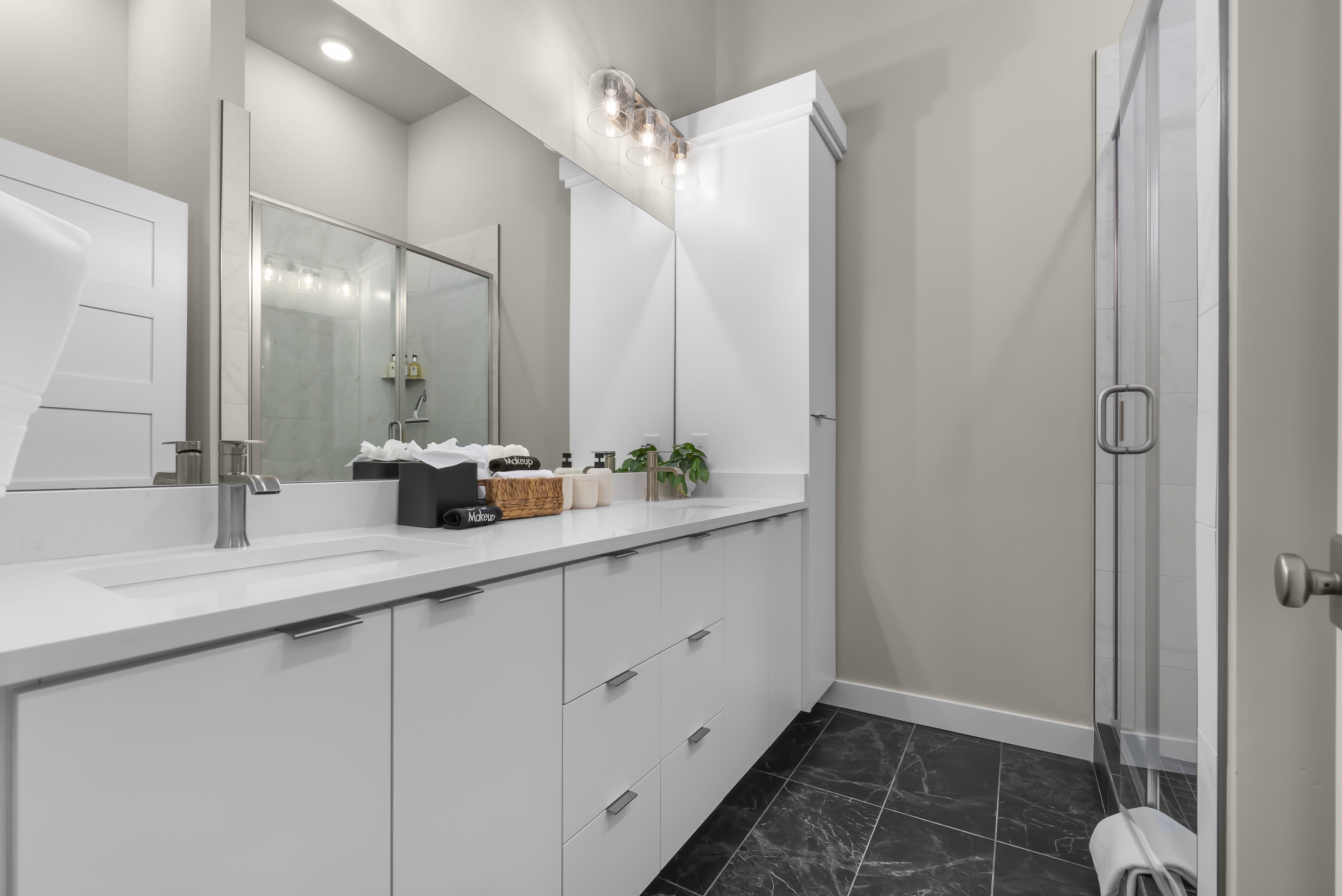 Bathroom featuring a shower stall, double vanity, and dark marble finish flooring