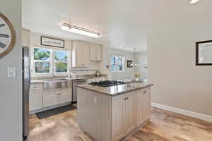 Kitchen featuring a center island with gas stovetop, granite countertops, tasteful backsplash, and Farm-style sink!