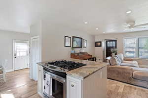Kitchen with white cabinets, gas stove, granite counters, recessed lighting, and light wood-style floors