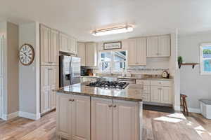Kitchen with granite counters, Farm-style sink, stainless steel appliances, light wood-style floors, and plenty of natural light