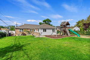 Rear view of property featuring a yard and a playground