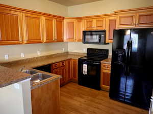 Kitchen with black appliances, brown cabinets, and light wood-style floors