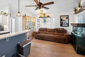 Living room featuring light wood finished floors, lofted ceiling, ceiling fan, and a wall mounted air conditioner