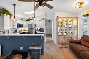 Kitchen with light countertops, vaulted ceiling, a kitchen breakfast bar, appliances with stainless steel finishes, and a peninsula