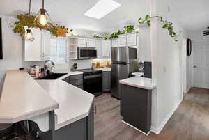 Kitchen featuring a peninsula, light countertops, a skylight, and open shelves