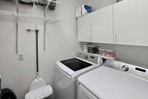 Washroom featuring separate washer and dryer, a textured wall, and cabinet space