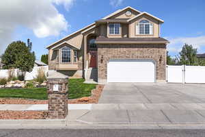 Traditional-style home featuring a gate, driveway, a garage, stucco siding, and brick siding