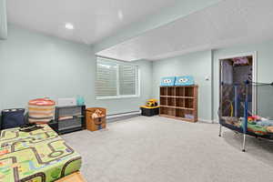 Rec room featuring carpet flooring, a textured ceiling, a baseboard heating unit, and recessed lighting