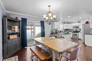 Dining area with crown molding, a chandelier, dark wood finished floors, and a textured ceiling