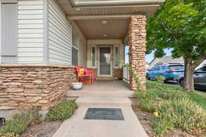 Entrance to property featuring stone siding and a porch