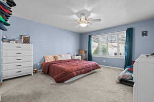 Bedroom with carpet flooring, a textured ceiling, and ceiling fan